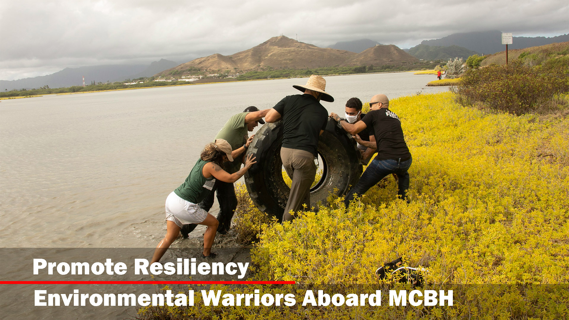 Volunteers push a tire out of the water during a Weed Warriors event aboard Marine Corps Base Hawaii