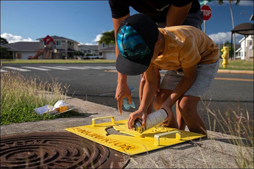 Volunteers apply a “No Dumping” sign during Operation Clean Water ‘Ohana. The purpose of the event is to protect resources and raise awareness of potential contaminants that wash down storm drains, ending up in the ocean. (U.S. Marine Corps photo by Lance Cpl. Clayton Baker)